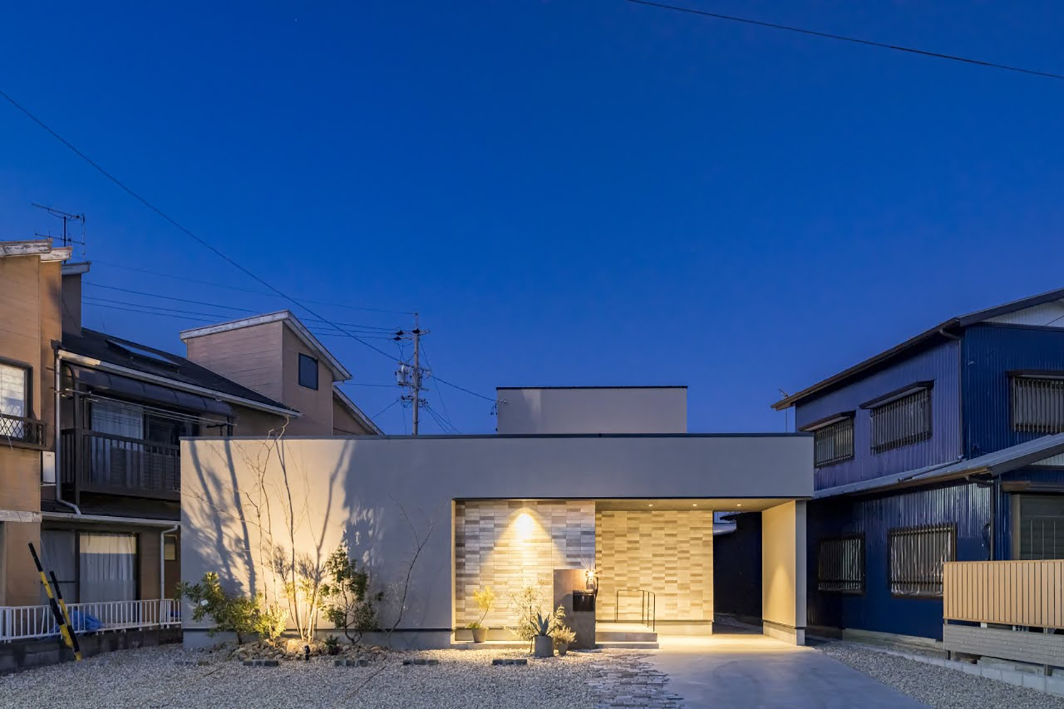ARRCH アーチ【浜松市中央区笠井町206-5・モデルハウス】笠井街道に向かう道路沿いに立つモデルハウス「余韻の家」は、通りすがる人も足を止めるほど、上品で洗練されたデザインが印象的。グレージュの塗り壁にアクセントタイルをあしらった外壁が上質感を演出し、ライトアップで浮かび上がる夜の外観もひときわ美しい