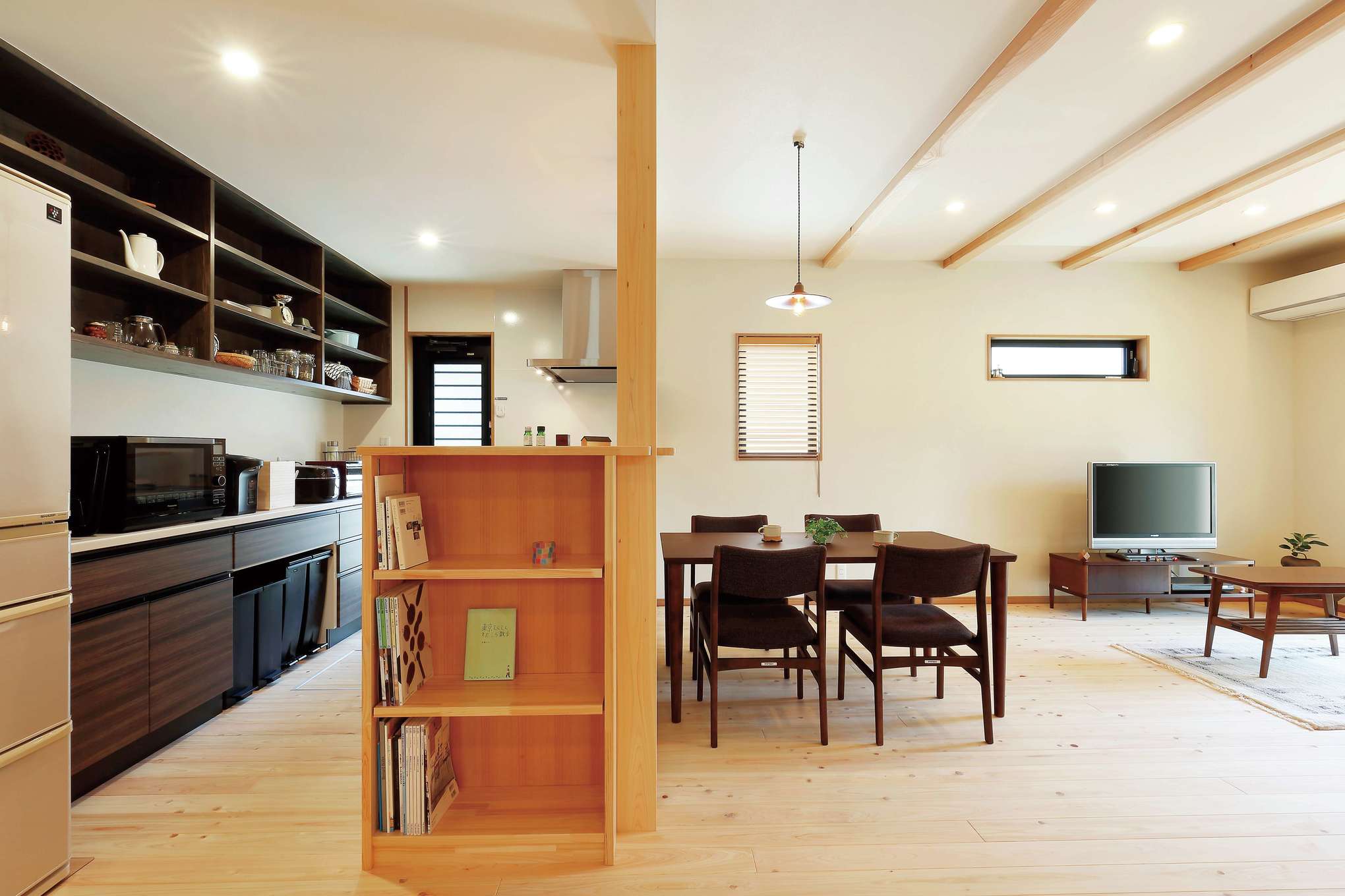 フジモクの家（富士木材）【デザイン住宅、収納力、自然素材】時間がゆっくりと流れるオール自然素材のLDK。ヒノキの床の経年変化も楽しみ。キッチンのデッドスペースを活かして本棚を造作し、食器棚の木の色を濃くしてアクセントをつけた