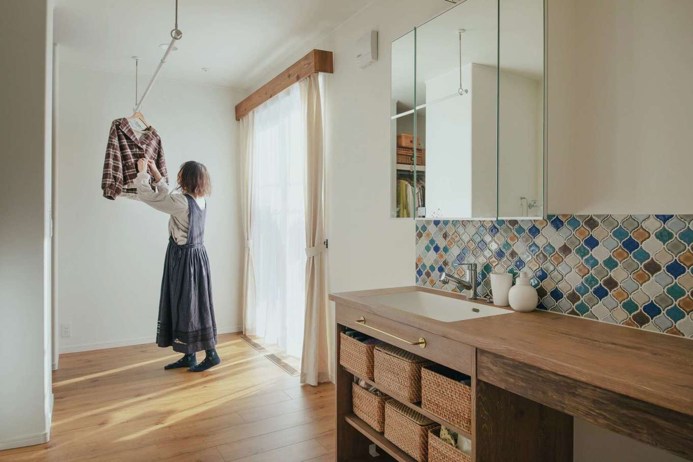 子育て安心住宅 Design Craft Office【デザイン住宅、子育て、間取り】タイル張りの洗面台を備える洗面脱衣室。窓の外には物干し場となるウッドデッキ。左手にファミリークローゼットを配し、洗濯効率もUP