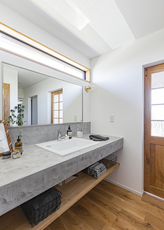 玄関すぐのモルタル調の造作洗面台は来客時にも便利