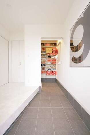 真っ白な壁と床に、三和土のグレーが映える玄関。奥の収納には、ご主人が集めているNIKEのスニーカーがずらり