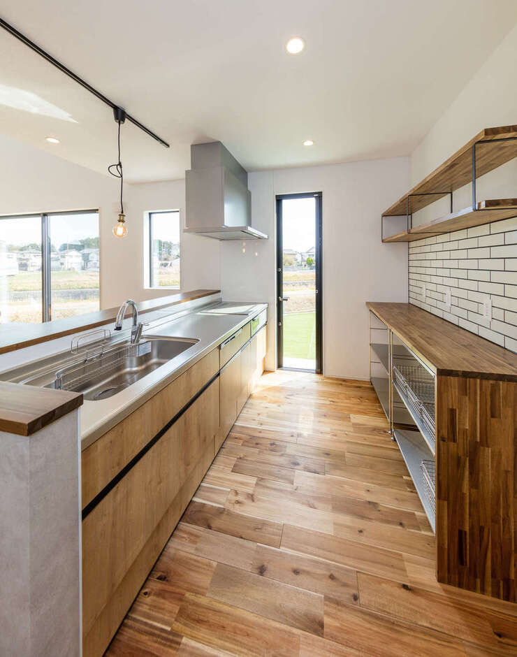 家族の気配を感じながら調理できるオープンキッチン。奥さまお気に入りのサブウェイタイルがアクセントに。勝手口からウッドデッキへとつながる洗濯動線も実現