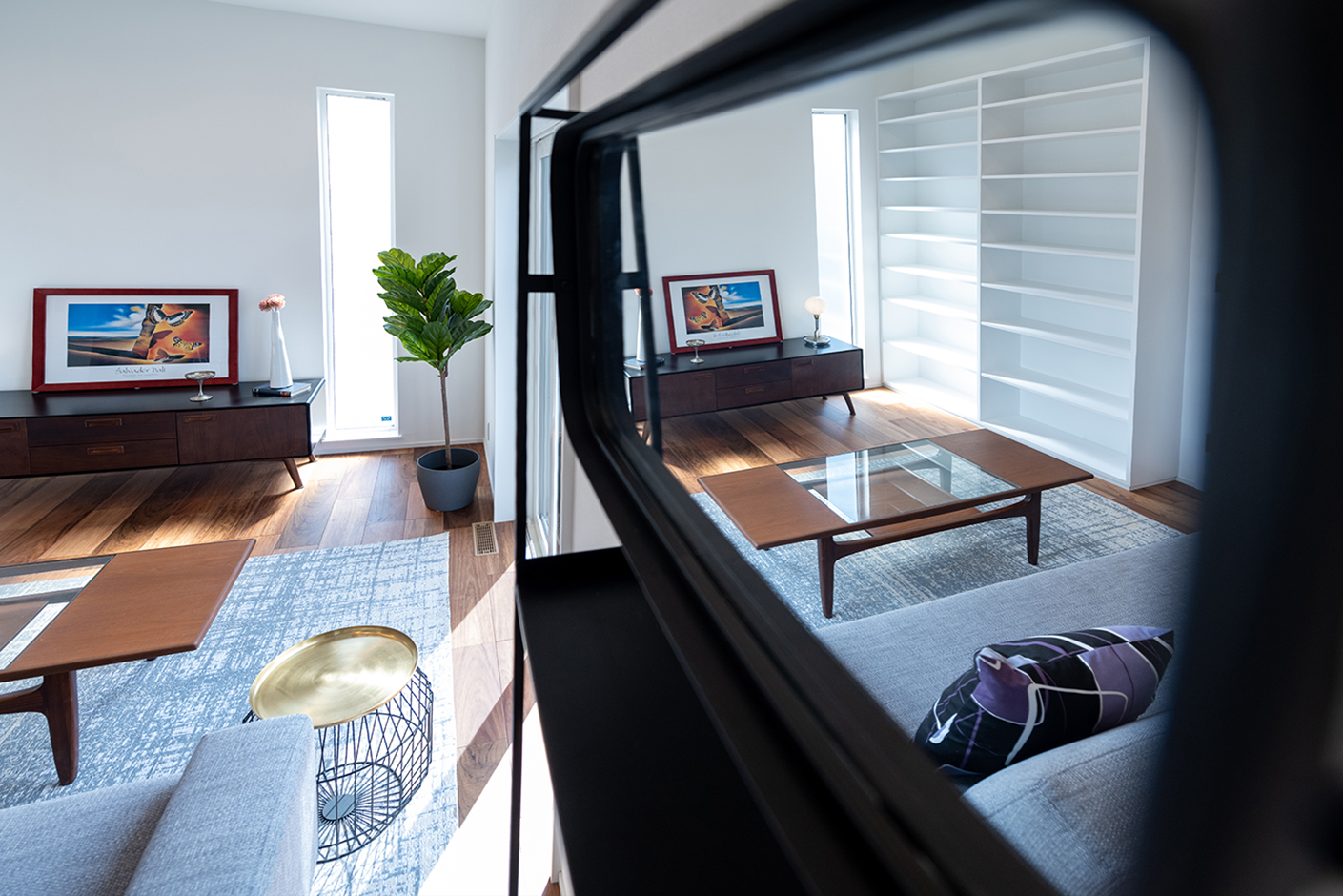 OWN RESORT HOME（オウンリゾートホーム）【デザイン住宅、趣味、間取り】鏡に反射したシンプルモダンなリビング。家具、照明、ブラインドは同社が運営するインテリアショップがコーディネートしたもの