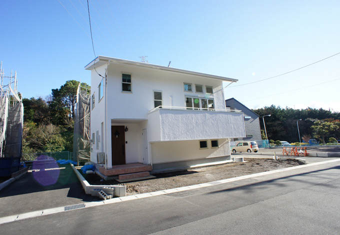 小野田産業～designers house project～【デザイン住宅、スキップフロア、インテリア】外壁はしっくい仕上げ。木目調の玄関ドアがアクセントに