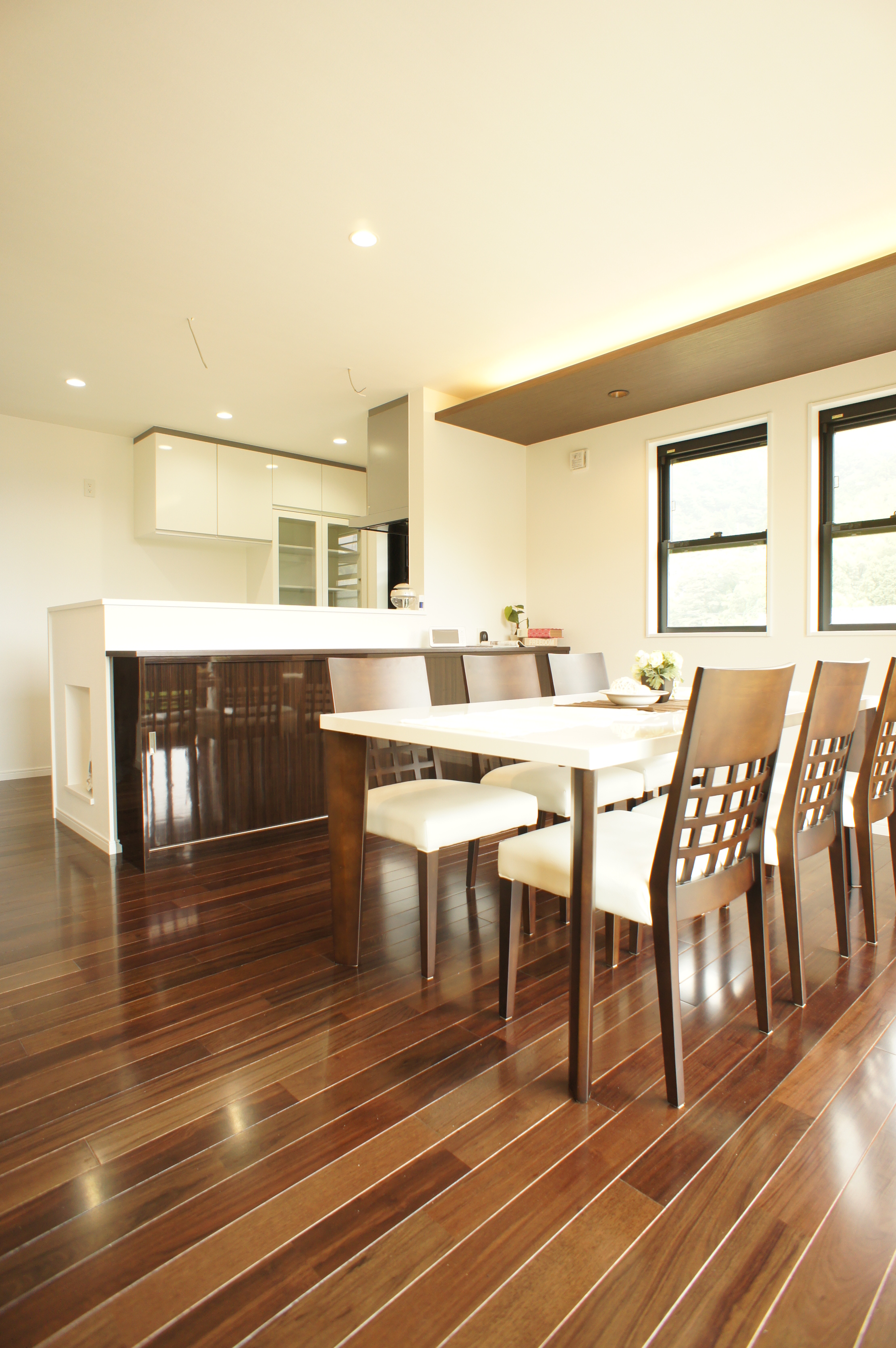 小野田産業～designers house project～｜ダークブラウンのフローリングが目を引くダイニングスペース。明るい自然光が心地よく、窓側の席でも快適な食事が楽しめる。