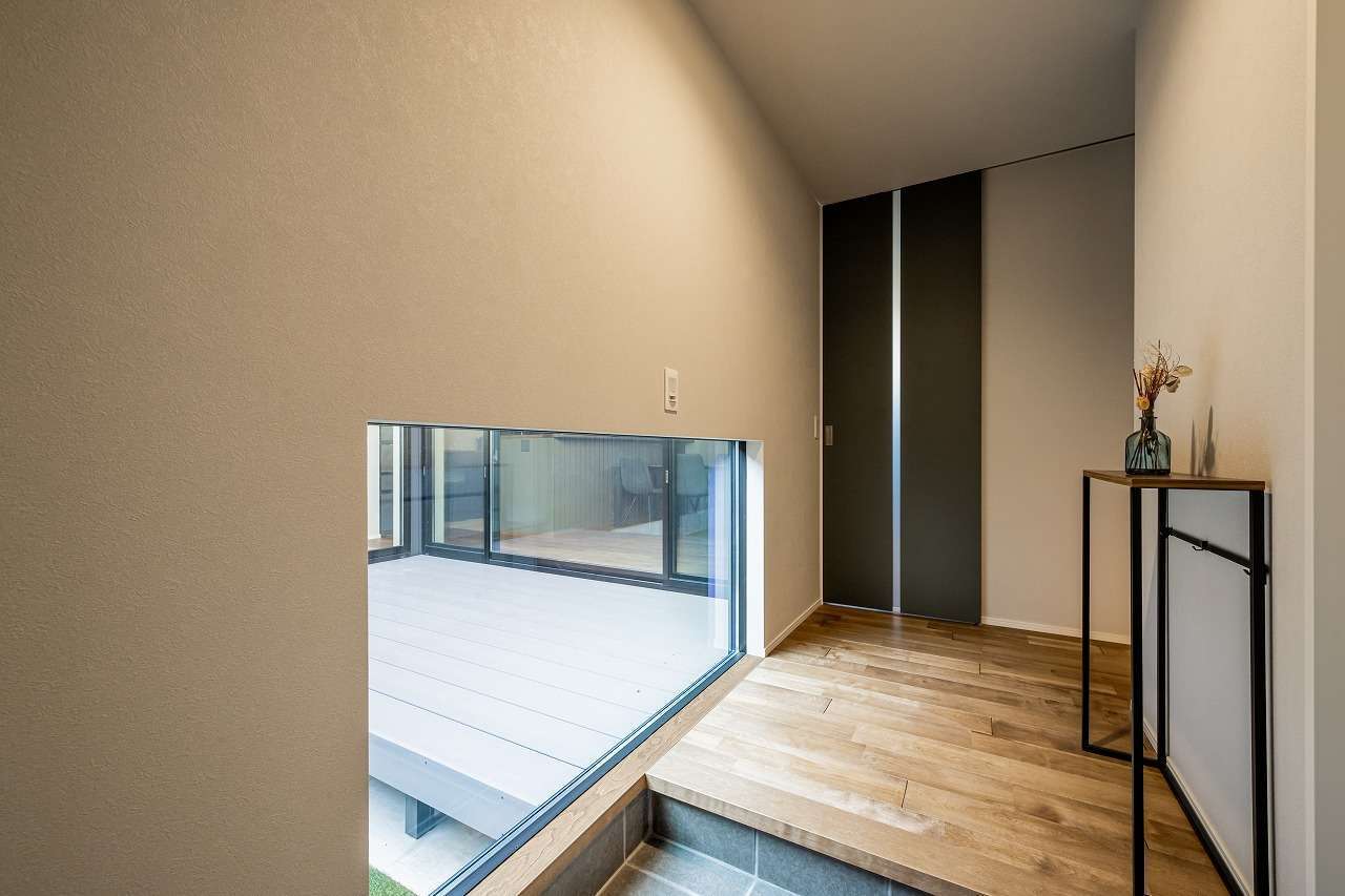 アーキテックス【デザイン住宅、趣味、間取り】地窓から中庭に視線が抜け、開放感と明るさを確保した玄関ホール。リビングドアは天井まで届くハイドアを採用