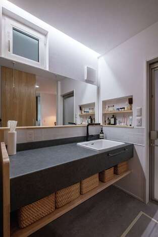 低燃費住宅静岡® TK武田建築｜モールテックス風のおしゃれな洗面台は、水とキズに強いメラミン化粧板を採用。壁一面のワイドな鏡はオーダー製作で、3人並んで歯磨きができる。深底のシンクは施主さん支給。玄関を入ってすぐの位置にあるので、子どもが泥んこで帰ってきてもリビングを汚す心配がない