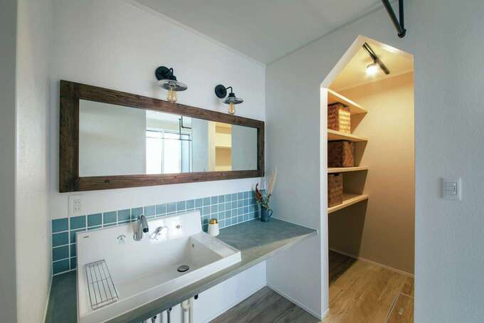 ランドリールームに設けた造作手洗いコーナー。ワイドな鏡とブルーのタイルがアクセントに。ファミリークローゼットに隣接して家事時間の短縮を実現