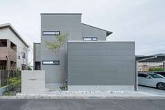 シャープで立体感ある佇まいが、周囲に住まい手のセンスを伝える。中庭を高い壁で囲い、通り側の開口部を限定することでプライバシーを確保。外壁には耐久性に優れる素材を使い、メンテナンス費用を抑えている。カーポートの奥にはドッグランがあり、キッチンからも出入りできる