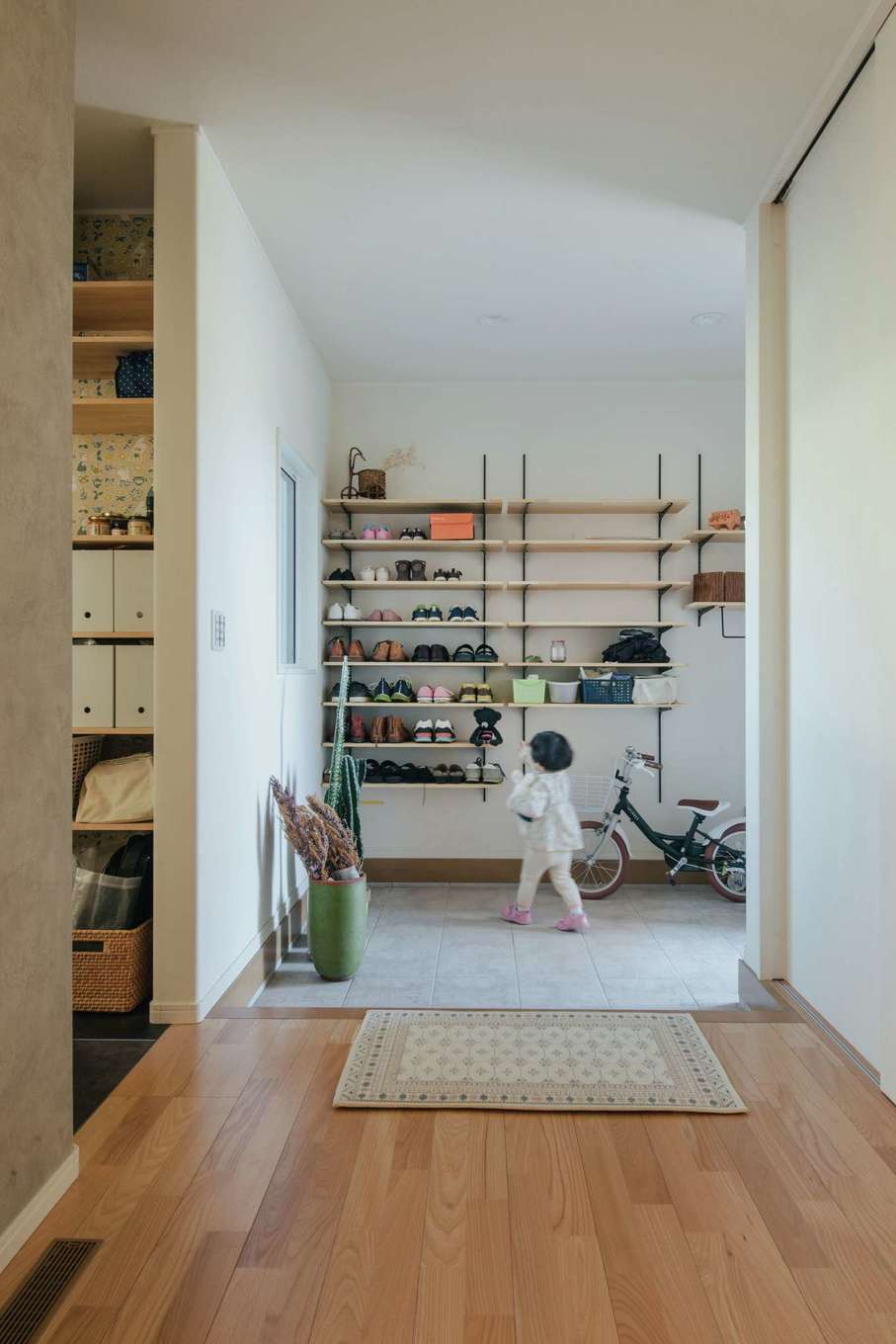 子育て安心住宅 Design Craft Office【デザイン住宅、子育て、間取り】間口の広い玄関が家全体の大らかさを生む。奥の棚はご主人が設置。左手はパントリー