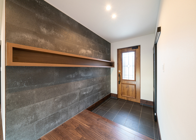 風合いのあるSOLIDがアクセントになった玄関ホール。飾り棚とのコーディネートをシャープに演出した