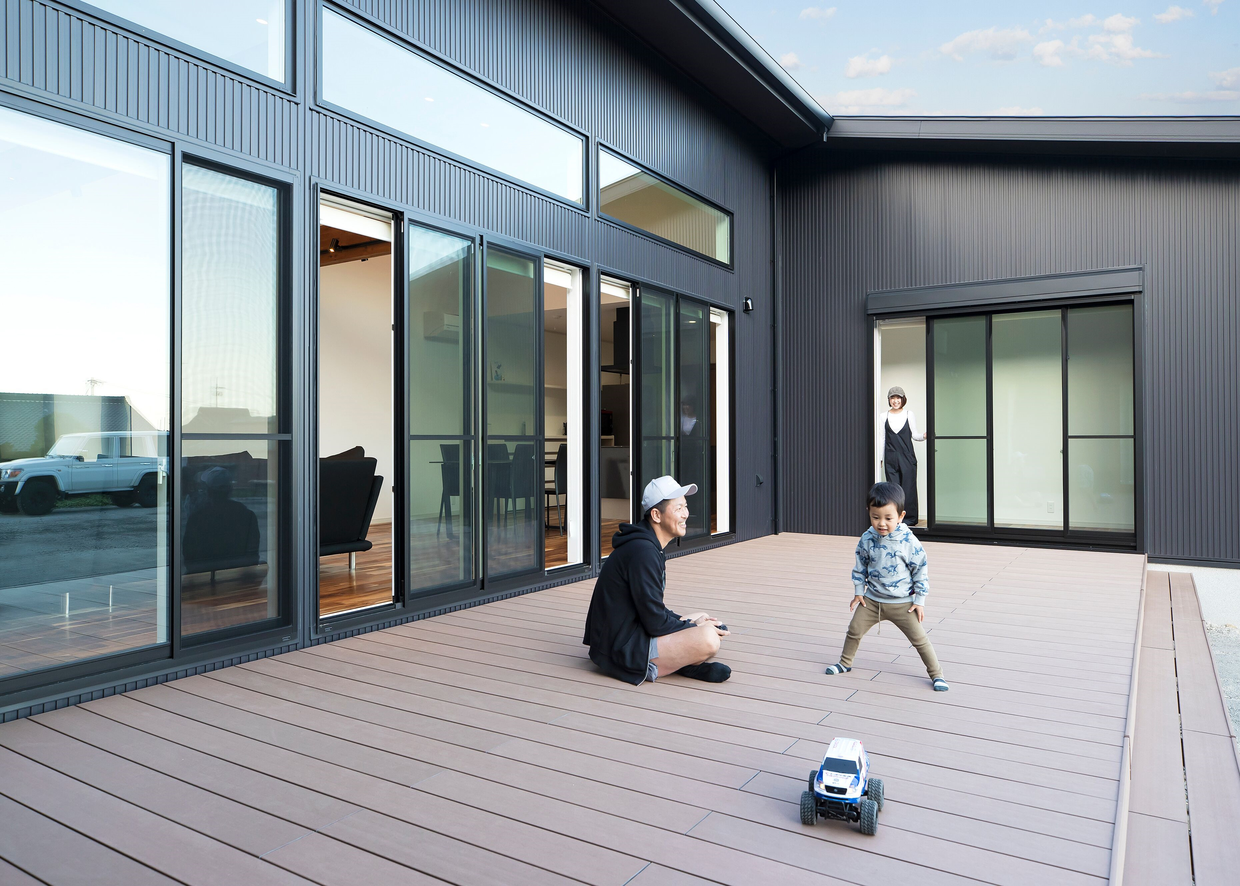 子育て安心住宅＆デザインラボ【デザイン住宅、間取り、平屋】中庭には広いウッドデッキを設け、コの字の3方向から出入りできるかたちに。どの部屋もデッキに繋がっているので、内と外との関係性が自然と身近になり、子どもも家にこもらず庭に出て、愛犬とのびのびと遊び回る機会が増えた