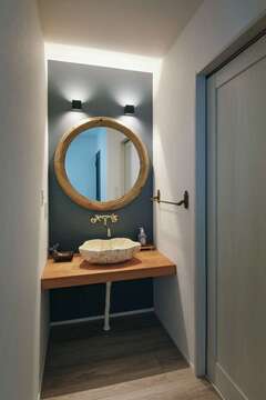 オリジナリティあふれる造作洗面台。水洗、ボウル、鏡、タオル掛けなど1つ1つのパーツを吟味し、間接照明も組み込んでもらった