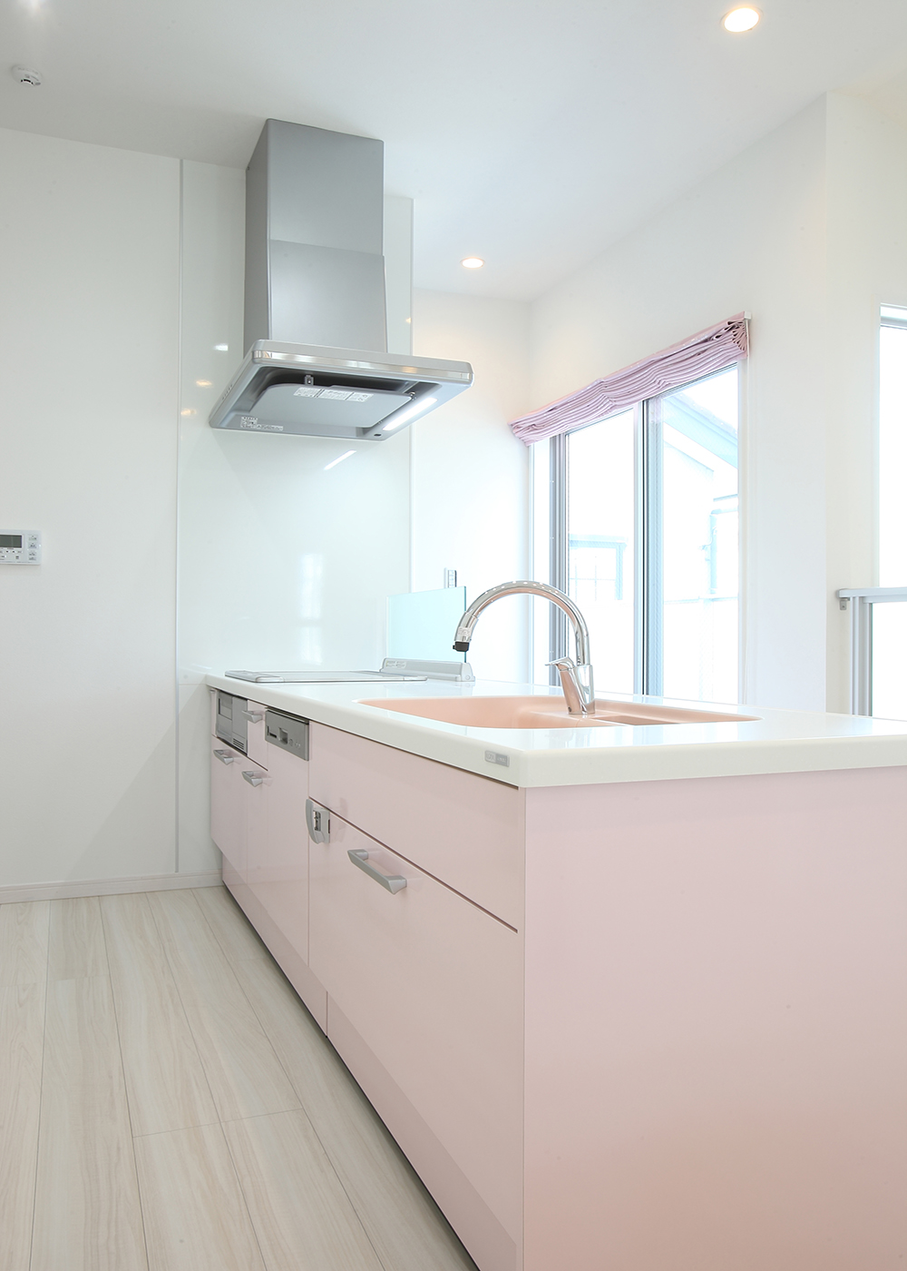 丸昇彦坂建設【デザイン住宅、間取り、インテリア】ピンク色を基とした可愛らしいキッチン。正面のカーテンと色を揃えることで浮くことなく統一されたデザインに