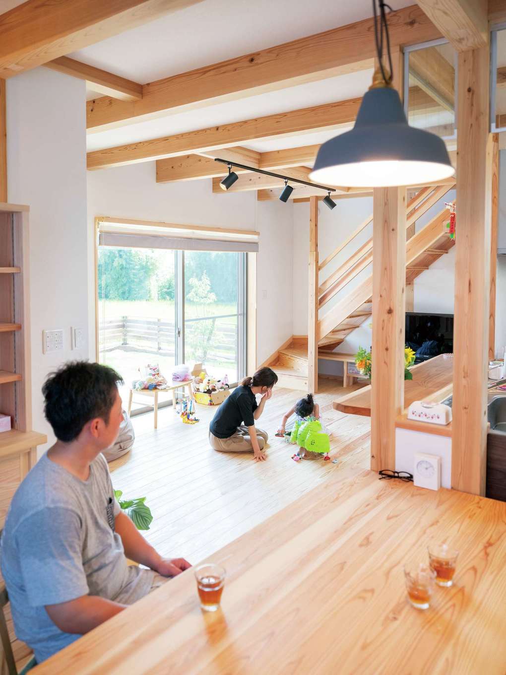 アクトホーム【子育て、自然素材、省エネ】ダイニングから見るリビング。オープン階段で開放感がアップ