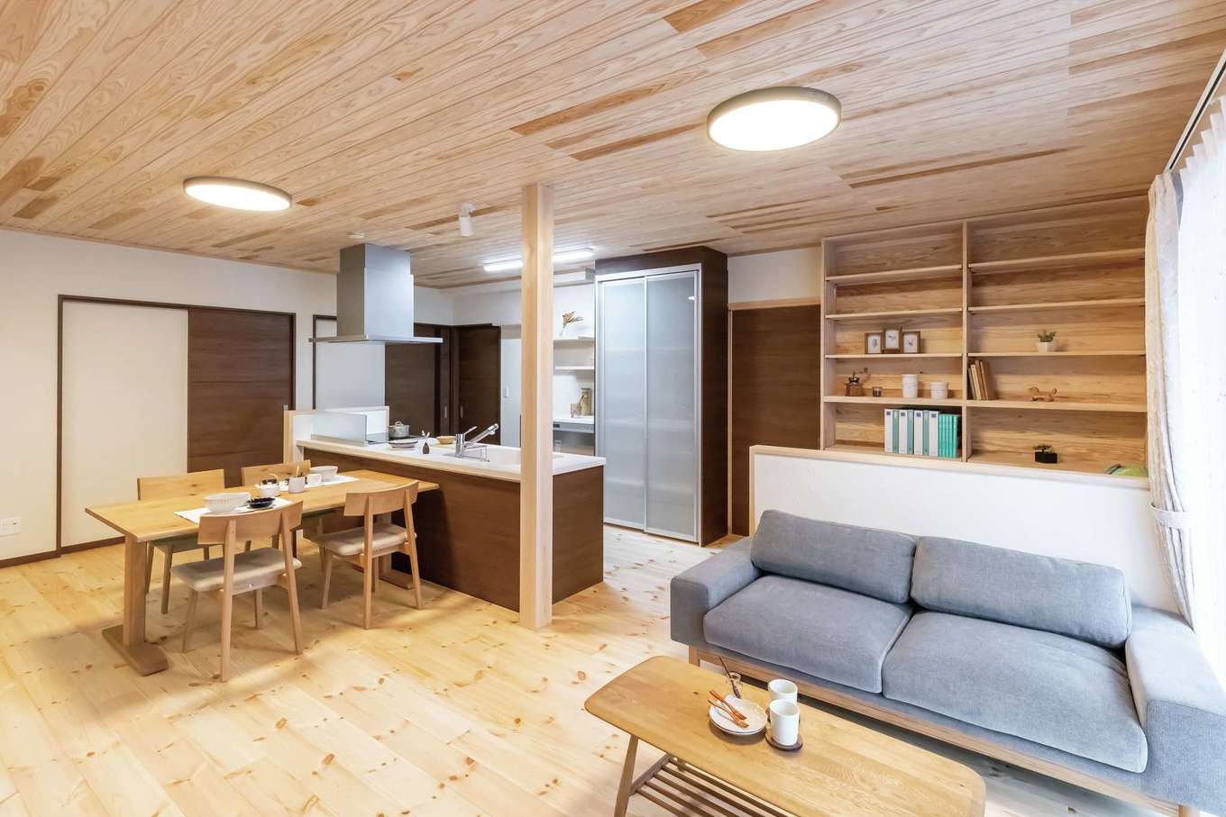 住まいるコーポレーション【子育て、二世帯住宅、自然素材】1階・親世帯のLDK。リビングの背面には書棚とカウンターが設けてあり、仕事や読書などに利用