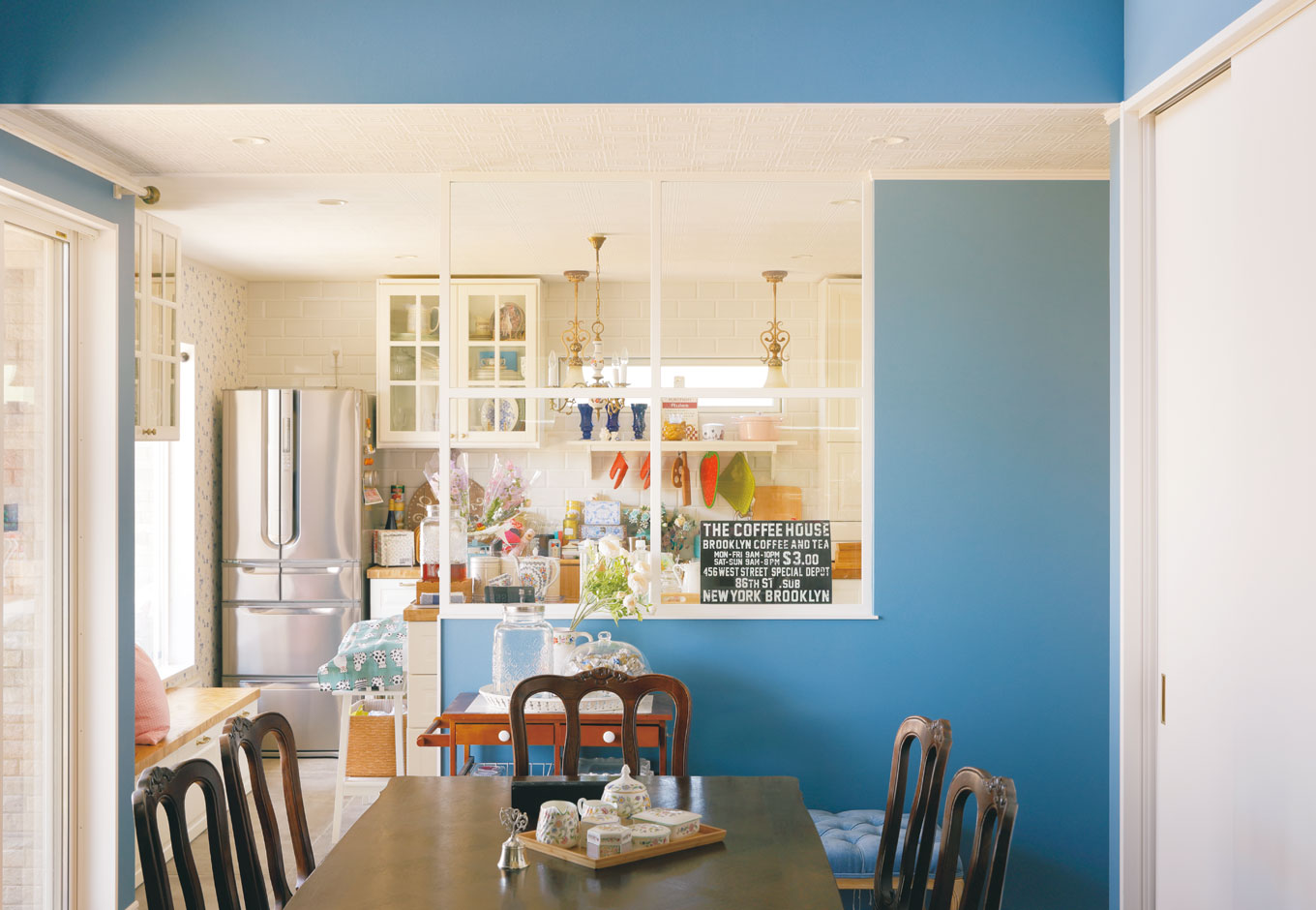 幹工務店【デザイン住宅、輸入住宅、インテリア】キッチンは独立型で、白を基調にデザイン。窓際のベンチの横には猫の出入口も確保した。ダイニングとの間にはガラス入り格子建具を設け、抜け感を強調