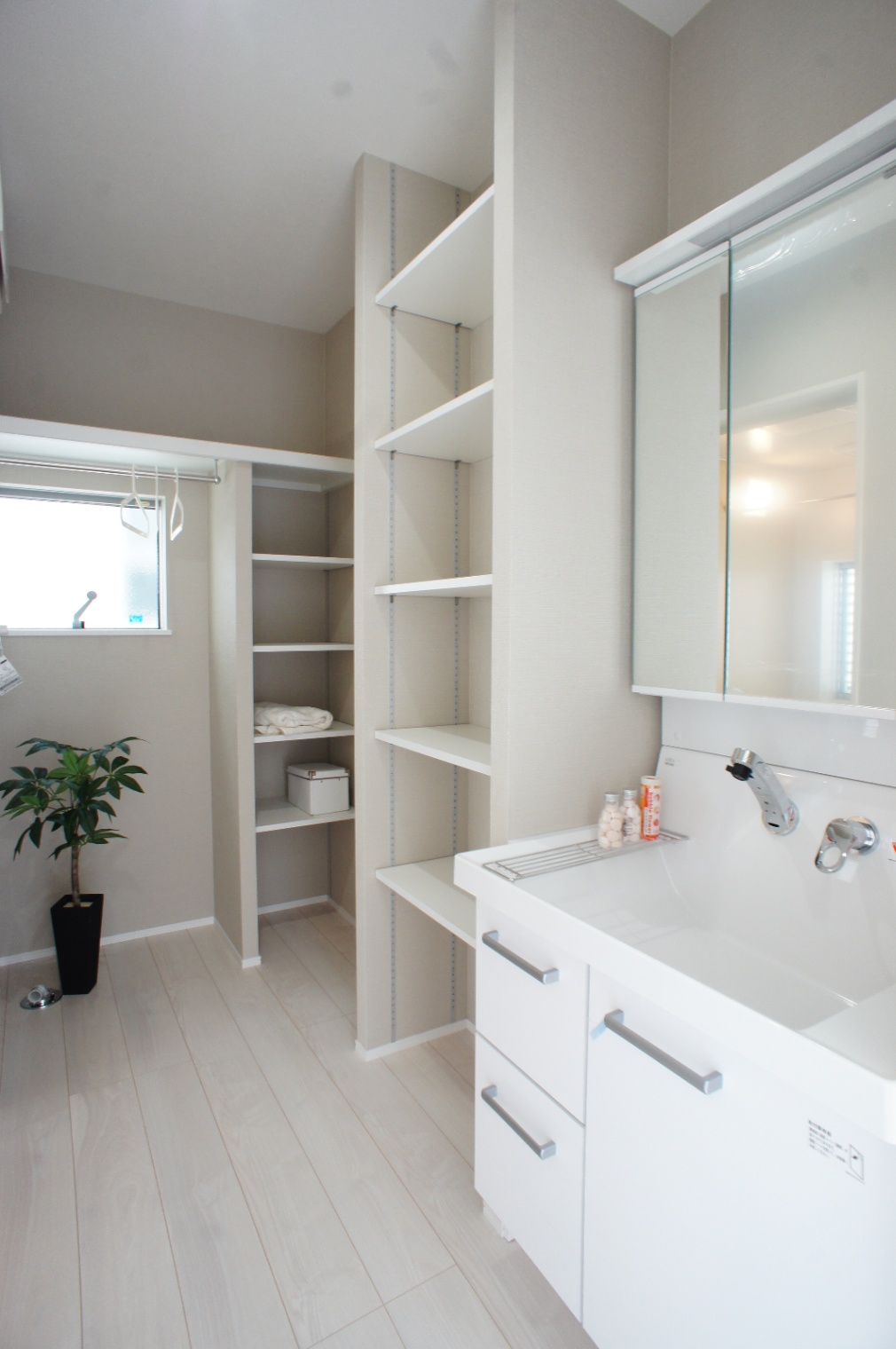 小野田産業～designers house project～｜グレージュ×ホワイトのモダンなデザインの洗面脱衣スペース。収納スペースが大きく確保されており、タオルや洗濯用品をすっきりと置くことができる。