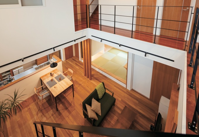 ダイナミックな吹抜けの大空間。毎朝、寝室から長い廊下を通って、1階へと降りていく気分は贅沢の極み。床は無垢のチーク、ダイニングテーブルはナラ材。アイアンの手摺が空間を引きしめている