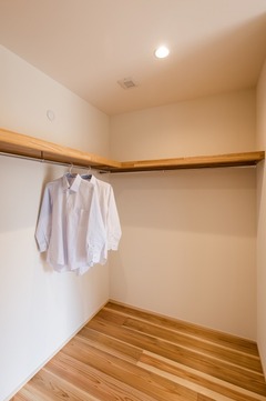 シンプルで使いやすいウォークインクローゼット。明るい木目の床材が採用されており、洋服の整理も容易で機能的な空間。