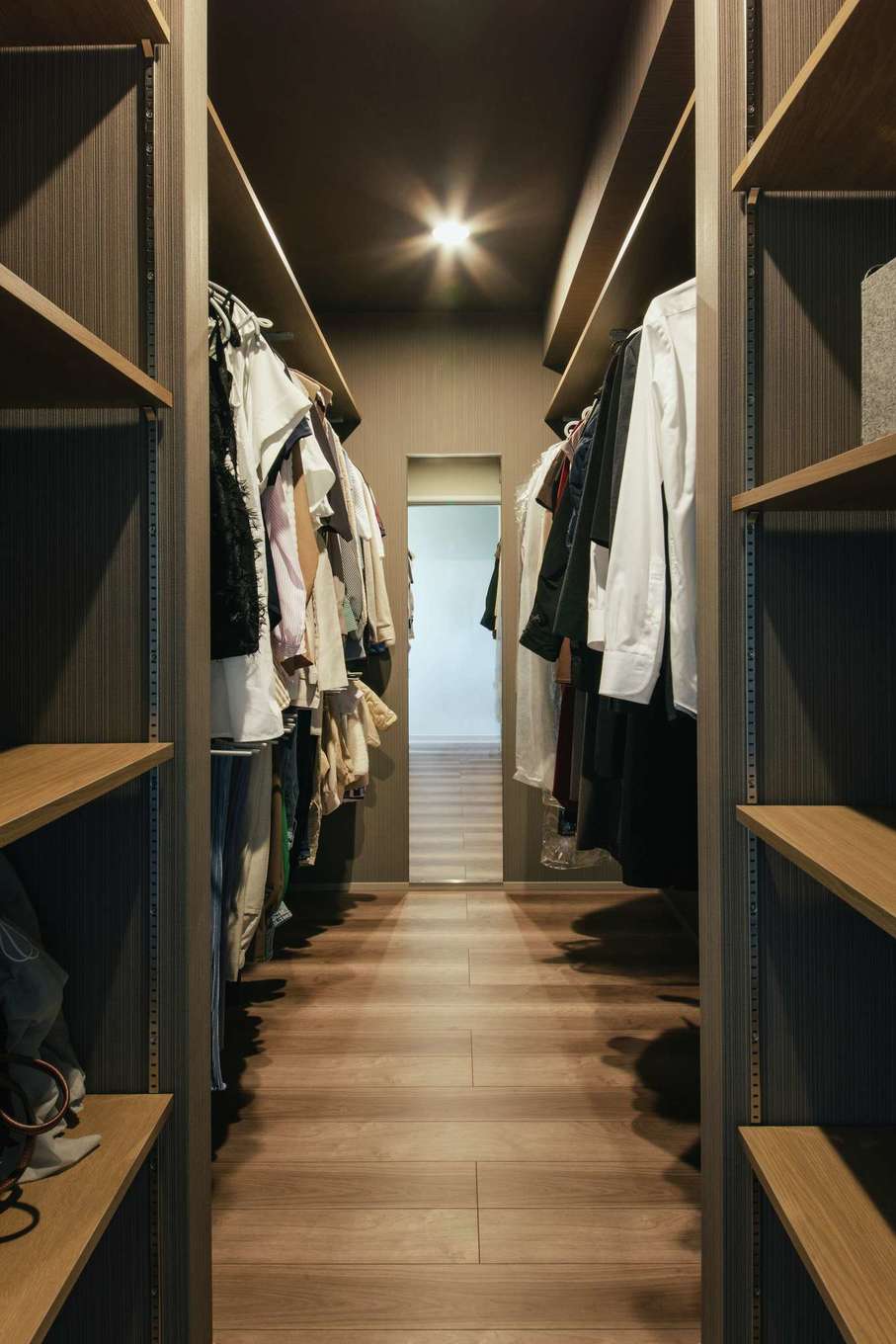 デザインハウス【デザイン住宅、間取り、インテリア】2階のファミリークローゼットは奥行きが長く、どこに何があるのかも一目瞭然。グレー系のクロスと木目の棚でアクセントをつけ、上品で落ち着いた空間に仕上げている