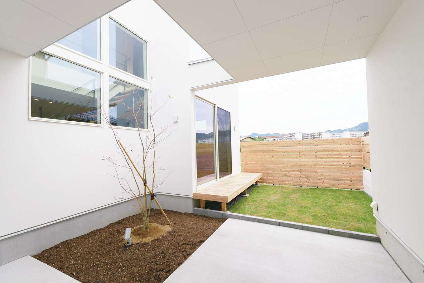 住家 JYUKA【デザイン住宅、間取り、建築家】駐車場から中庭を臨む。周囲をウッドフェンスで囲み、隣接する住宅からの視線も気にならない工夫が