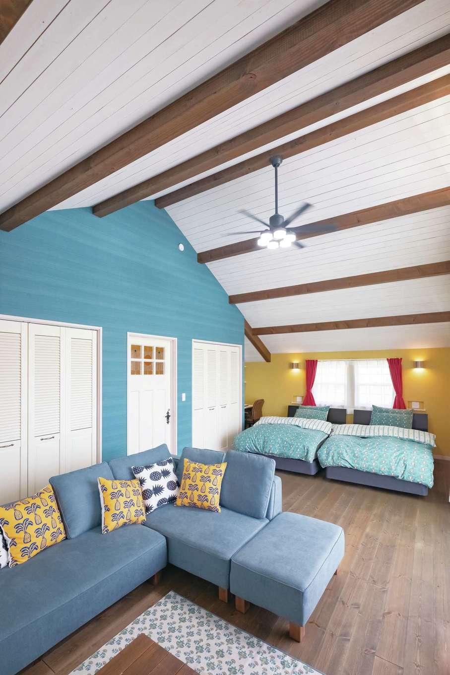 富士ホームズデザイン【デザイン住宅、子育て、インテリア】夫妻の寝室兼リビング。勾配天井が開放感を、床や天井はもちろん家具やカーテンまで吟味したカラーコーディネートがリゾート感をもたらす。奥には造作のデスクを用意