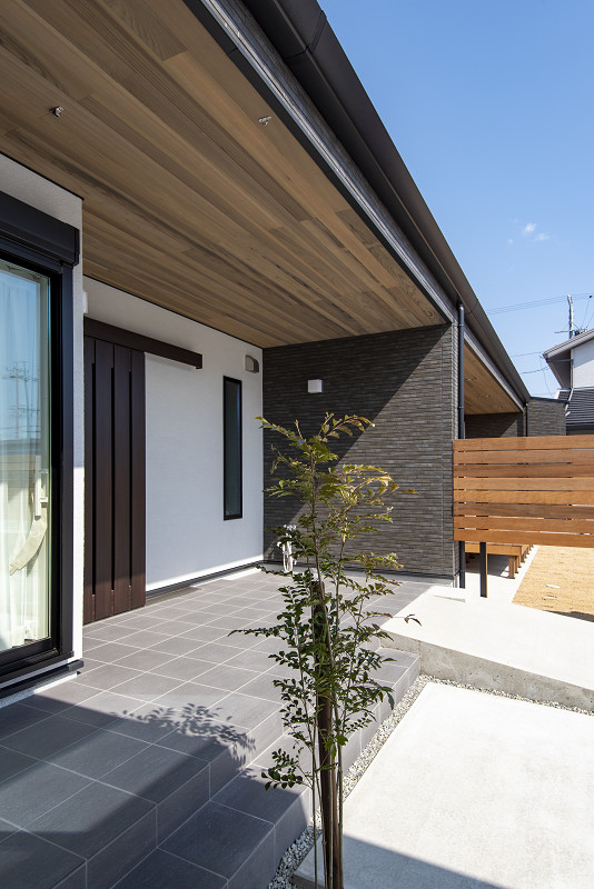 トキワハウス デザイン アンド ビルド（常盤工業）｜ナチュラルな色合いの外壁と天井で構成された住宅の外観。周囲には木々が植えられ、自然と調和したデザインが魅力的である。