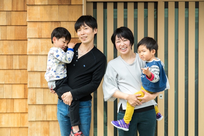 縦格子の玄関建具と米杉鎧張りの外壁が印象的な玄関前で記念撮影
