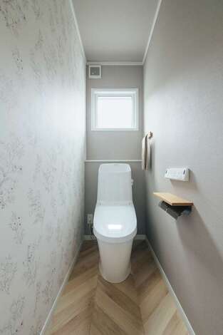 ボタニカル柄のクロスとヘリンボーンの床がおしゃれなトイレ空間