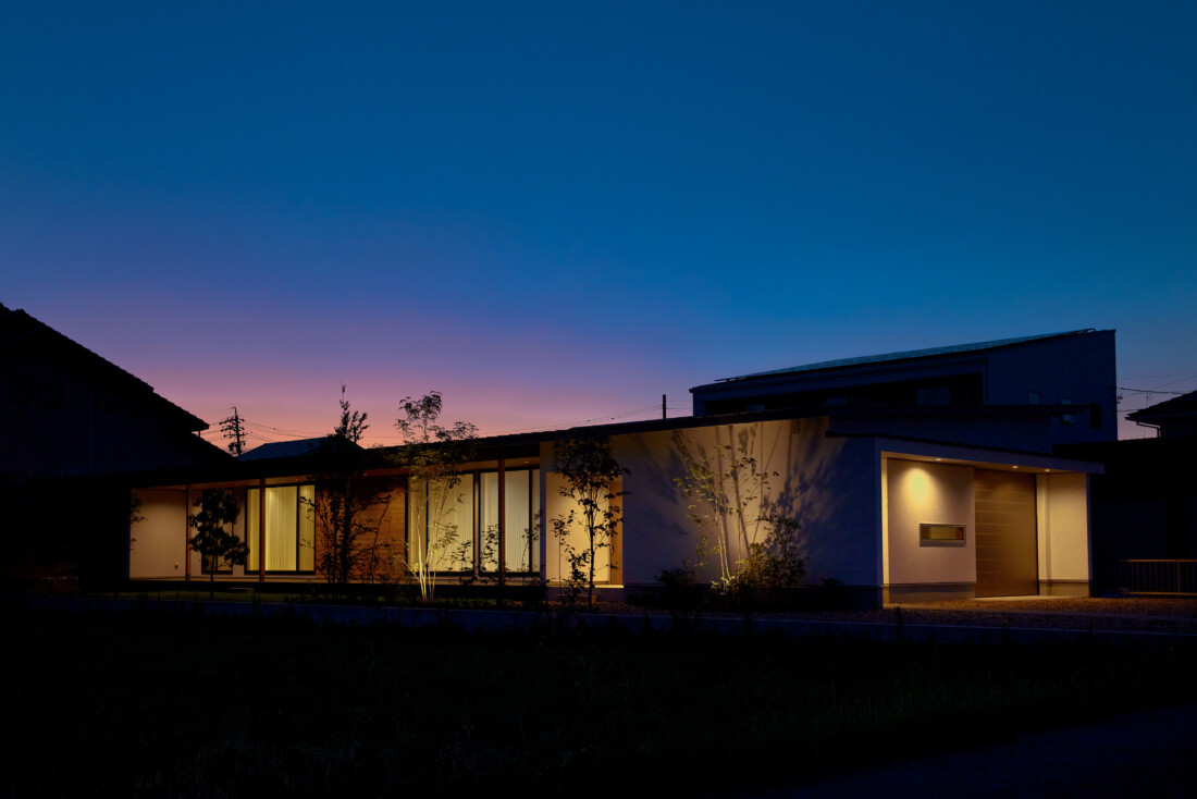 チェックハウス｜夕暮れ時にライトアップされたモダンな住宅の外観。シンプルながらも洗練されたデザインが印象的