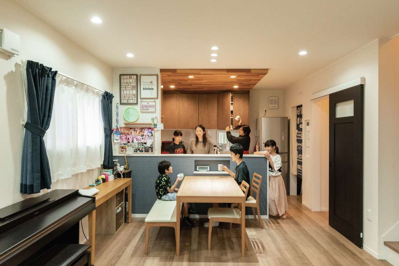 臼幸産業【デザイン住宅、子育て、間取り】キッチンは下がり天井で空間に変化を付けた。デニム調の壁紙がダイニングにくつろぎ感を演出。パントリー収納も設置