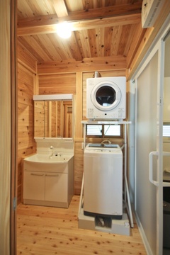 シンプルながら木のぬくもりが感じられるランドリールーム。洗面台と乾燥機付きの洗濯機が設置され、効率的な家事動線をサポート。