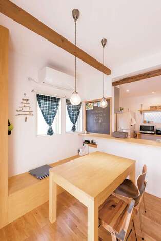 ダイニングテーブルと併せて、ベンチシートも造作で。座面を上りかまちのアールも優しい雰囲気を醸し出しているげれば便利な収納スペースが顔を出す。黒板ペイントの伝言板は家族のコミュニケーションツール