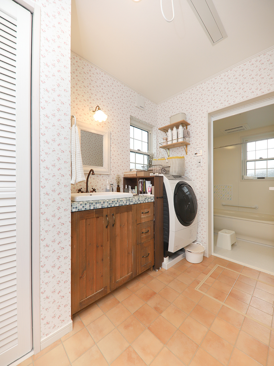 アサヒグローバルホーム｜キッチンの奥にレイアウトした洗面室、アンティークな雰囲気を演出した洗面台。花柄のアクセントクロスがぱっと目を引く明るい空間に仕上がった