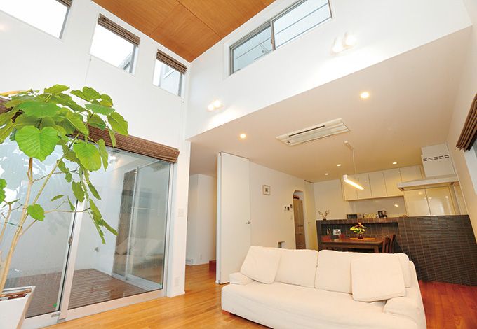 -delphi- デルフィ（藤井建築事務所） 【デザイン住宅、間取り、建築家】吹き抜けやウッドデッキへと視線が伸び、実際の広さを上回る開放感。上部に設けられた窓は、プライバシーを確保しながら明るさを室内へと招き入れる。タイル貼りのキッチンは空間を引き締めつつ、役割を分割する