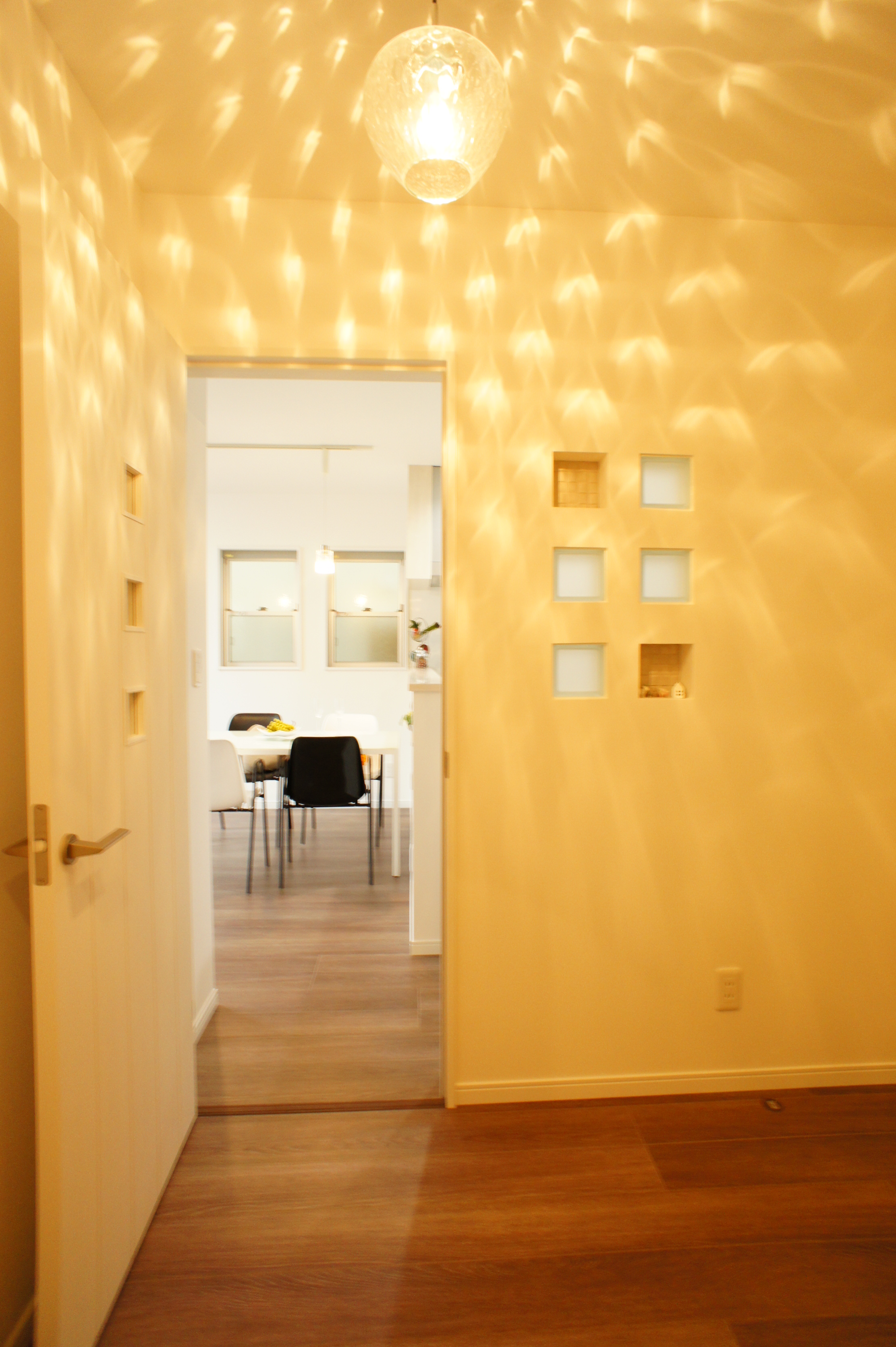小野田産業～designers house project～｜柔らかな光が美しい廊下。壁に取り入れられた小さな窓がアクセントとなり、奥のリビングダイニングへの期待感を高める。