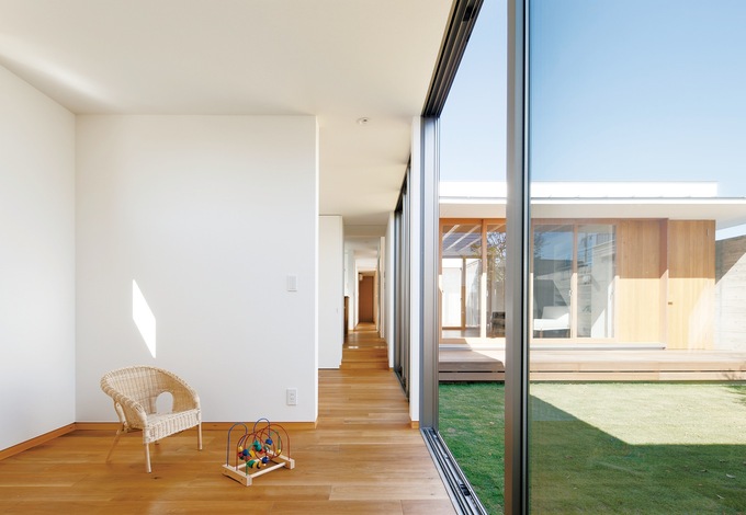 ガレージから突きあたりの寝室まで直線に見通せる西側の廊下。右手に中庭、左手は子ども部屋2つ、ダイニングキッチン、バスルームが並ぶ