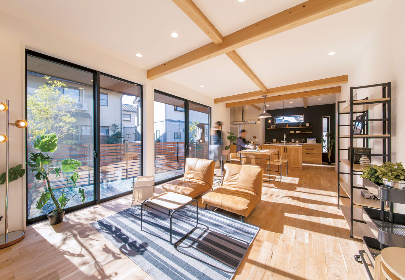 住たくeco工房【1000万円台、デザイン住宅、自然素材】クルミ無垢材のフローリングが美しい22畳のLDK。照明や家具など奥さまのコーデセンスが光る。梁は天竜材をラフな仕上げで。窓は通常の1.5倍幅、高さ2250cm。この大開口部も、樹脂サッシLow-Eペアガラスだから断熱も十分