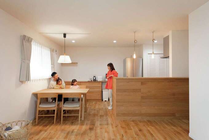 板張りの腰壁が無垢の空間に調和したダイニングキッチン。窓から広い庭を見渡しながら、楽しく食卓を囲む毎日が家族の絆を強くする。テーブル背面の造作収納は、ゴールドの取手にこだわった