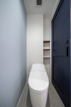 シンプルで清潔感のあるトイレ空間。柔らかな色合いと収納棚がポイントで、機能性とデザイン性を両立している。