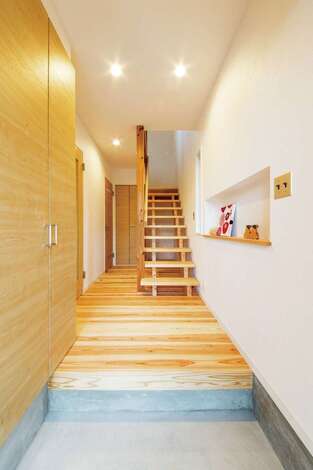 シンプルに仕上げた玄関ホール。職人手づくりのストリップ階段は目線が抜け、開放感を生み出す。階段下のデッドスペースも収納に。おしゃれなアメリカンスイッチプレートはご主人からのリクエスト