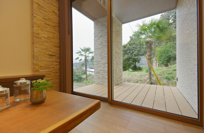 ガラスの掃き出し窓から見えるウッドデッキ。室内と庭をつなぐ開放的な空間で、自然と一体化したリラックスできるスペース。