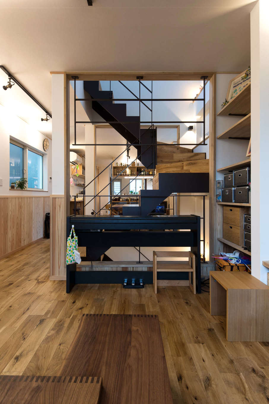 建築システム（狭小住宅専門店）【収納力、狭小住宅、鉄骨鉄筋コンクリート構造】空間を緩やかに仕切るのは鉄骨階段。手前はリビング、階段の奥にダイニングとキッチンが広がる。床には自然の風合いを活かした無塗装のナラ無垢材を。天井は土佐和紙を張った