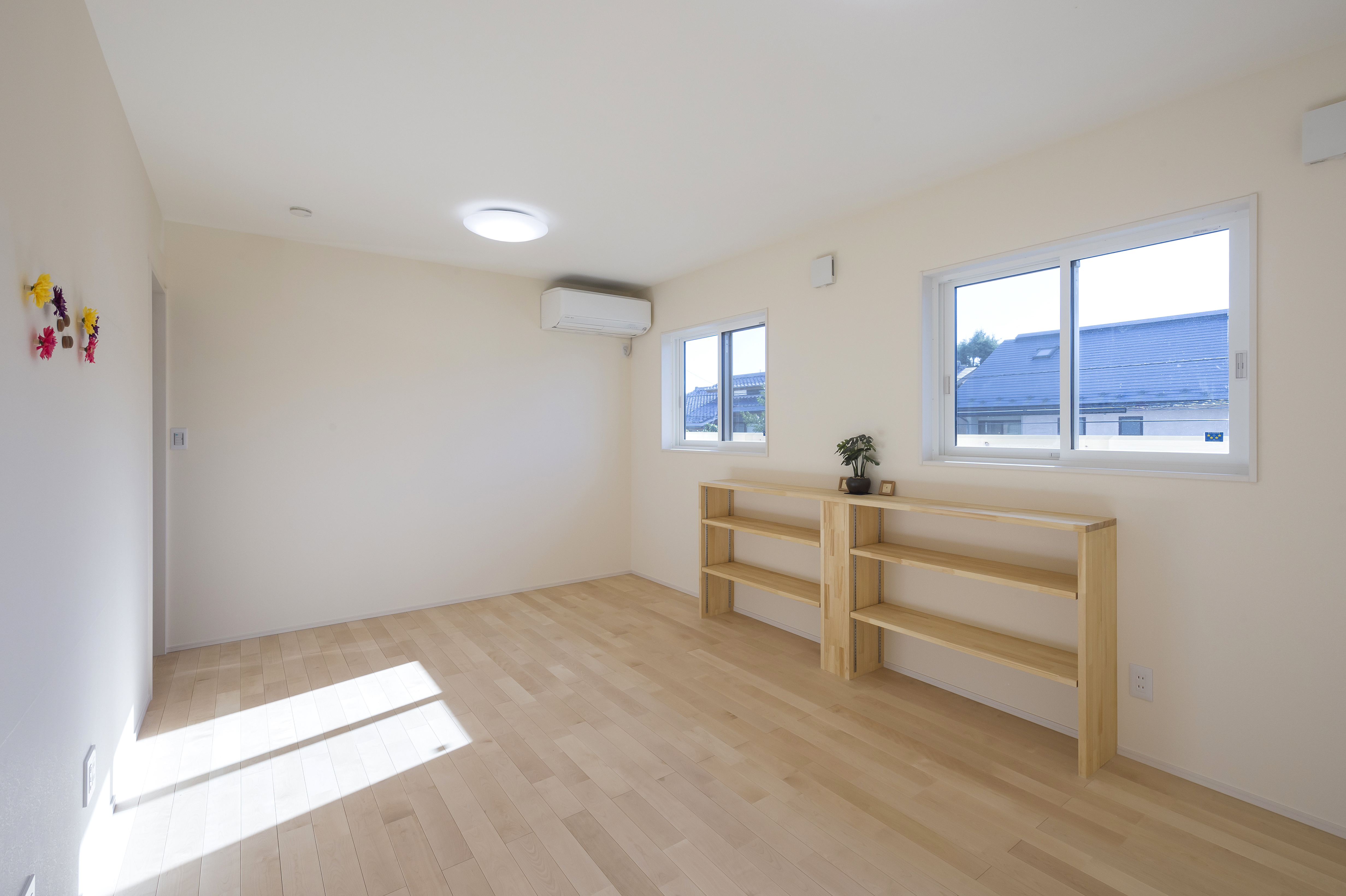 しあわせの住まい一級建築士事務所｜明るく開放的な子ども部屋。窓から差し込む自然光が心地よく、壁にある収納棚が実用的である。シンプルなデザインで、自由に飾り付けを楽しめる空間。