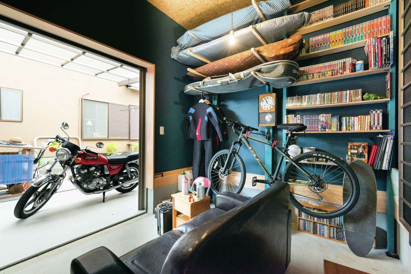 福工房【趣味、自然素材、平屋】サーフィンをはじめ多趣味なご主人。駐車場からも出入りできるガレージハウスのような土間部屋を用意。これまで家の中のいろいろな場所に点在していた趣味のものをここに集約した。ソファに座って、ひとりのんびり過ごすことも