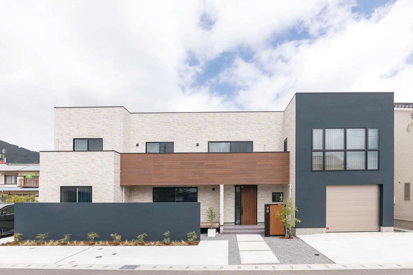 ハートホーム【デザイン住宅、二世帯住宅、ガレージ】100坪の敷地に建つワイドスパンのM邸。夜になると外壁の腰壁がライトアップされ、植栽の陰影が美しく写り込む