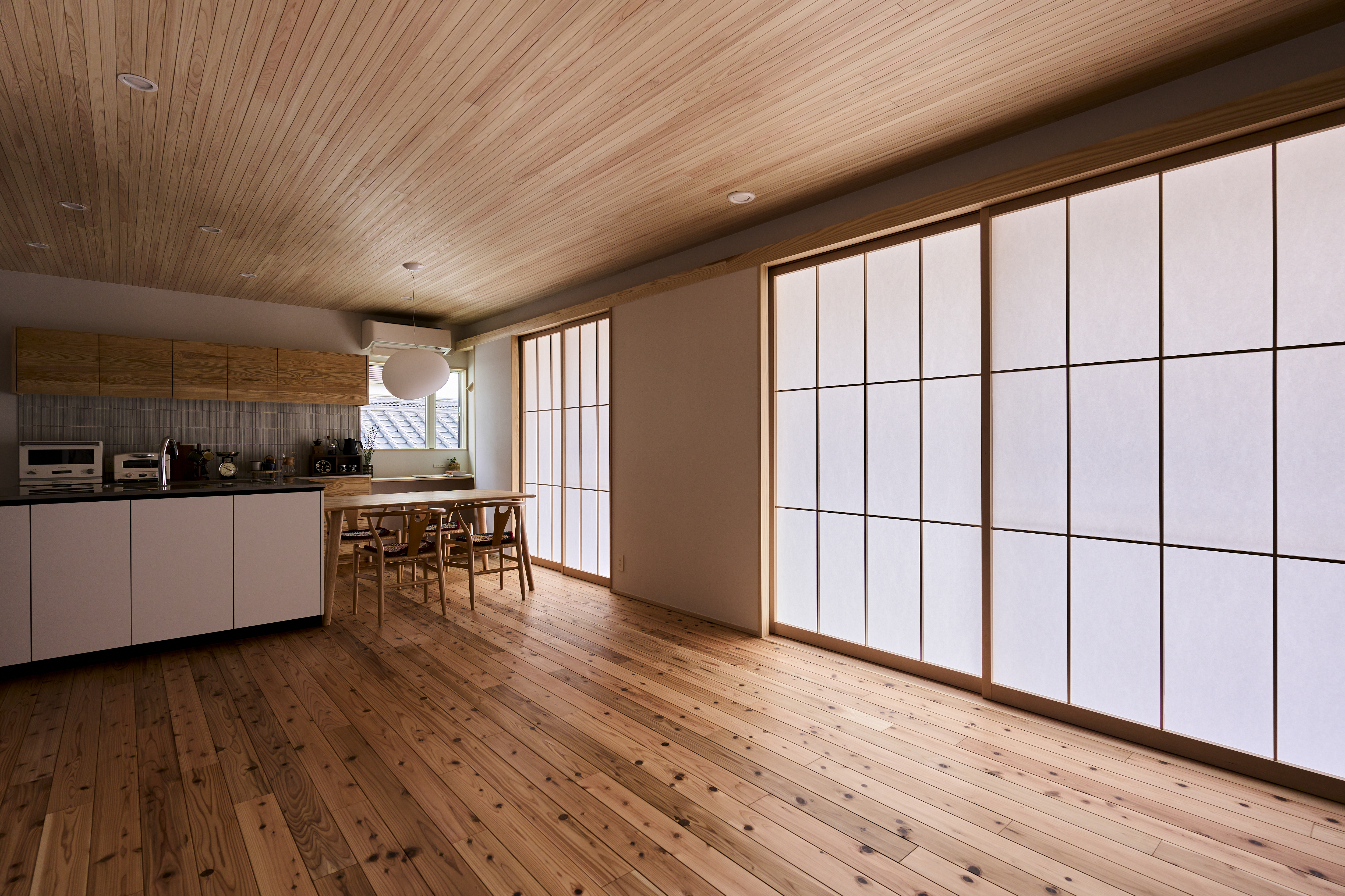 KEN建築工房｜広々としたリビングダイニング。和風の障子が温かみを与え、自然光を優しく取り入れる。木目の床と天井が調和しています。