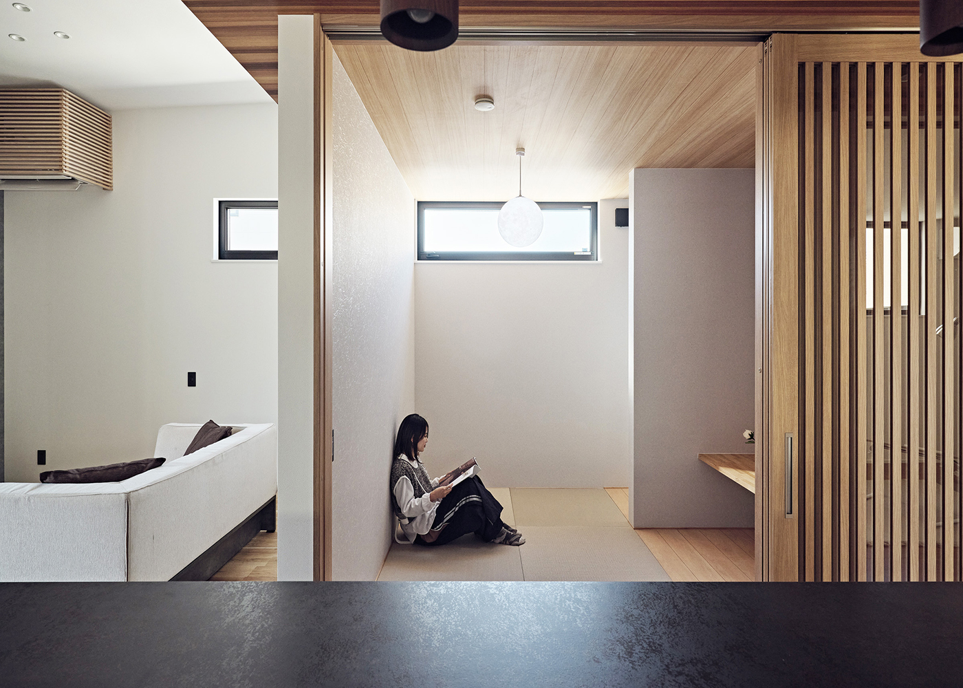 平屋建築ブルーハウス【和風、建築家、平屋】格子戸やキッチンと一体化した折り下げ天井が落ち着きを感じさせる和室。リビングに隣接し、キッチンからも目が行き届くため、子どもの遊び場やお昼寝のスペースとしても活躍。カウンター付きで、大人時間をゆったりと楽しむこともできる