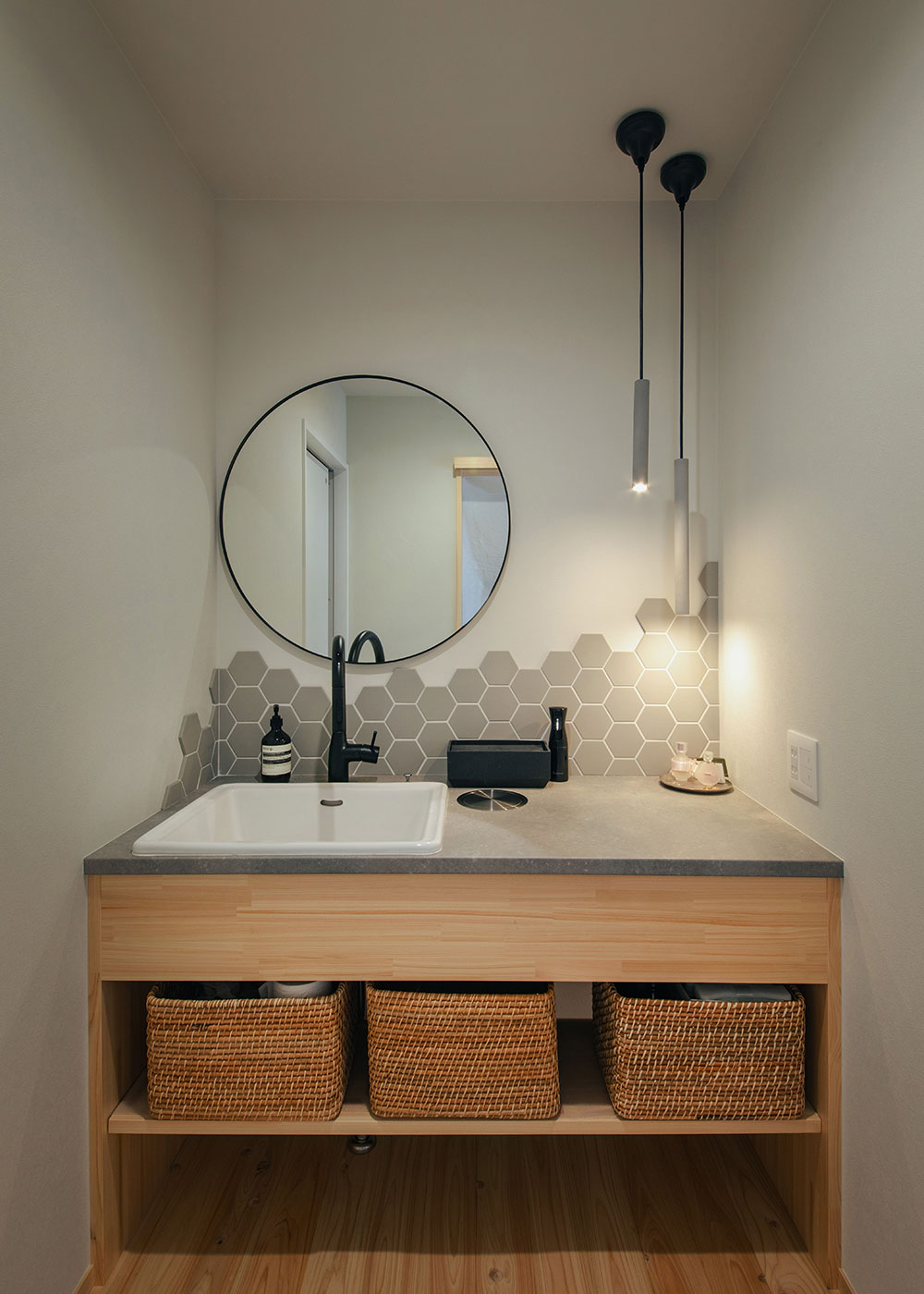 フジモクの家（富士木材）【趣味、自然素材、間取り】モノトーンのタイルや水栓、照明でまとめた、スタイリッシュな造作洗面台。LDKの入口かつトイレの横にレイアウトされ、建物の奥にあるよりもずっと使いやすい